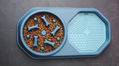 Mavi köpek maması kasesi, kemik ayırıcıları ve koyu yüzey yalama paspası..