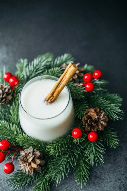 Sonsuz yeşil çelenk dekorasyonunda tarçın çubuğuyla şenlikli kremalı kış içeceği.