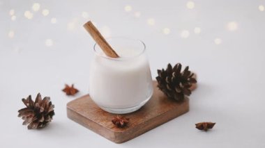 Bardakta sıcak kış içeceği, tarçın çubuğu, kozalak, yıldız anason, neşeli ışıklar.