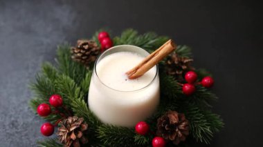 Yeşil çelenk ve kırmızı böğürtlen içinde tarçın çubuğu bulunan kremalı kış içeceği.