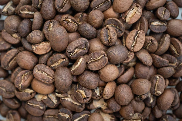 Full frame shot of light roasted coffee beans. Roasted beans smell like coffee, and weigh less because the moisture has been roasted out. They are crunchy to the bite, ready to be ground and brewed.