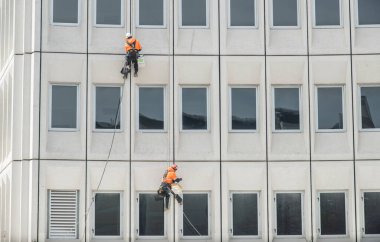 Christchurch, Yeni Zelanda 'daki hasarlı binayı onarmak için duvardan iple inen iki adam..
