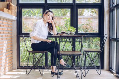 Modern ofiste oturan ve kameraya bakan melez iş kadınının portresi..