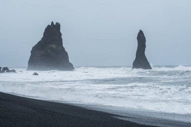 Reynisfjara ya da Güney İzlanda 'nın Kara Kum Sahili ikonik kaya oluşumuyla Reynisdrangar dramatik bir ruh hali içinde ve gökyüzünde.