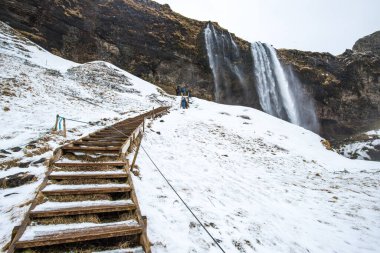 İzlanda 'daki Seljalandsfoss şelalesinin arkasına gitmek için yürüyüş yolu İzlanda' nın en ünlü doğa yerlerinden biridir..