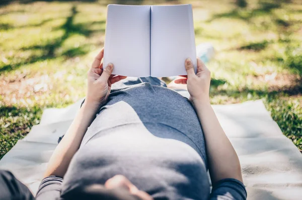 Przycięty Widok Młodą Kobietę Ciąży Leżącą Trawie Ogrodzie Otworzyć Czytać — Zdjęcie stockowe