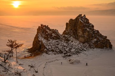 Rusya, Sibirya 'nın kış mevsiminde donmuş Baykal Gölü' nde kutsal bir yer olan Şaman Kayası 'nın günbatımı manzarası.