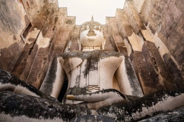 Wat Si Chum Tapınağı 'nın çatısındaki devasa Buda heykeli Sukhothai tarihi parkının kuzey bölgesinde, duvarlarla çevrili şehrin dışında yer almaktadır..