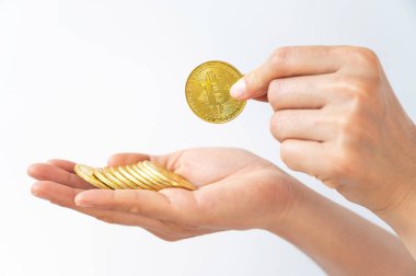 Birisi beyaz arka planda izole edilmiş altın Bitcoin jetonu tutuyor. Bitcoin popüler bir kripto para birimi, sanal para birimi veya dijital para birimidir..