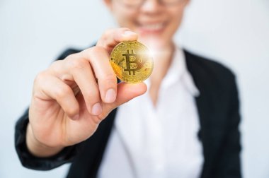 Altın Bitcoin jetonu tutan mutlu bir iş kadını. Bitcoin popüler bir kripto para birimi, sanal para birimi veya dijital para birimidir..