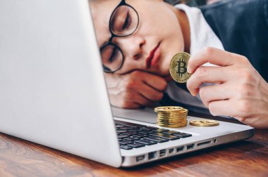 Endişeli iş kadını masasında yatıyor ve Bitcoin jetonu arıyor..