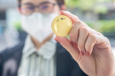 İş kadını elinde bir Dogecoin simgesi tutuyor. Dogecoin bir şifreleme para biçimidir, bir tür dijital para, bitcoin gibi, ama şaka olarak yaratılmış..