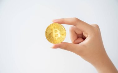 Beyaz arka planda izole edilmiş altın bir Bitcoin jetonu tutan biri. Bitcoin popüler bir kripto para birimi, sanal para birimi veya dijital para birimidir..