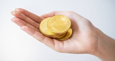 Birisi beyaz arka planda izole edilmiş altın Bitcoin jetonu tutuyor. Bitcoin popüler bir kripto para birimi, sanal para birimi veya dijital para birimidir..