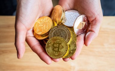 Kişinin elinde çeşitli kripto para jetonlarının olduğu yakın çekim. Kripto para birimi, kriptografi ile korunan dijital veya sanal para birimidir..