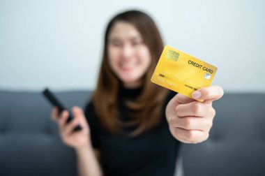 Cep telefonu uygulamalarından alışveriş yapmak için kredi kartını gösteren Asyalı bir kadın. Kredi kartı, müşterilerin borç para almasına izin veren bankalar tarafından sağlanan bir kredi kurumudur..