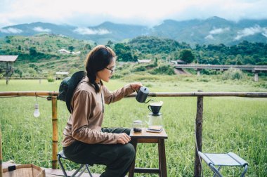 Tayland 'ın Nan ilinin Sapan köyünde kamp yaparken damlatan bir kahve yapan genç Asyalı kadın..