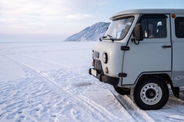 Rus UAZ minibüsü Baykal Gölü 'nün buz yüzeyine park ediyor. Rus UAZ Rusya 'nın sert çevrelerindeki pürüzlülüğüyle popüler bir araçtır..