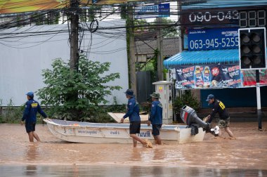 Chiang Rai, Tayland: 13-Eylül-2024: Kurtarma ekibi Tayfun Yagi saldırısından sonra küçük bir tekneyi çekiyor ve sel basmış yolda yürüyor.