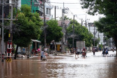 Chiang Rai, Tayland: 13-Eylül-2024: Tayland halkı Tayfun Yagi saldırısından sonra sel basmış yolda yürüyor.