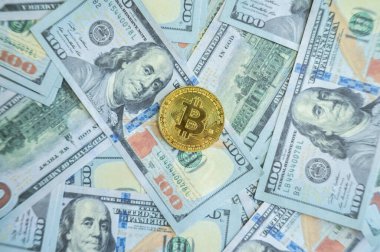 Amerika 'ya 100 dolarlık banknot üzerine yerleştirilmiş bir Bitcoin jetonu. Bitcoin, herhangi bir merkezi denetim veya banka veya hükümet denetimi olmadan çalışan dijital para birimidir..