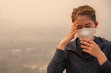 Kötü hava kirliliği (PM2.5) nedeniyle başı ağrıyan Asyalı kadın. PM2.5 seviyesi hava kalitesinin sağlığa zararlı olduğu anlamına geliyor..