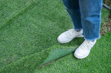 Cropped shot view of someone standing on incomplete green artificial turf. Artificial grass are made by polyethylene or nylon, convenient and it does not require much maintenance. clipart