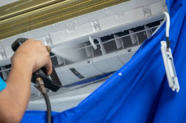 Teknisyenlerin klima filtresi için yüksek basınçlı su sıkarken çekilmiş görüntüsü. Klimana su püskürterek kir ve diğer döküntüleri temizliyorsun..