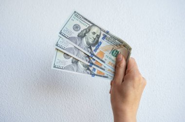 Beyaz duvara karşı Amerikan doları banknotları tutan birinin görüntüsü. ABD Doları, ABD 'nin para birimidir..