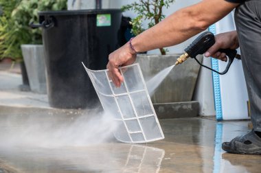 Teknisyen, klima filtrelerini temizlemek için yüksek basınçlı su tabancası kullanıyor. Klimana su püskürterek kir ve diğer döküntüleri temizliyorsun..