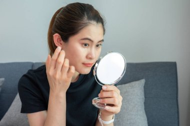 Asyalı kadın gözlerinin altına yaşlanma önleyici krem sürüyor. Yaşlanma önleyici krem cilt yaşlanma belirtilerini azaltmak, maskelemek veya önlemek için kullanılır.