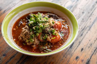 Masada bir kase Khanom Jeen Nam Ngeow (Kuzey Tayland Baharatlı Erişte Çorbası) servis edilir. Baharatlı Erişte Çorbası Tayland-Yai 'den etkilendi. Bu yemek artık ikonik bir Kuzey Tayland yemeği oldu..