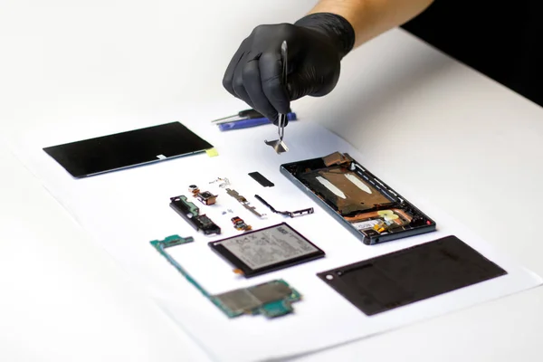 Tamirci. Defocus teknisyeni laboratuvarda akıllı telefonun ana kartını tamir ediyor. Cep telefonu, elektronik, onarım, güncelleme ve teknoloji. Bozuk akıllı telefon bileşenleri sökülüyor.