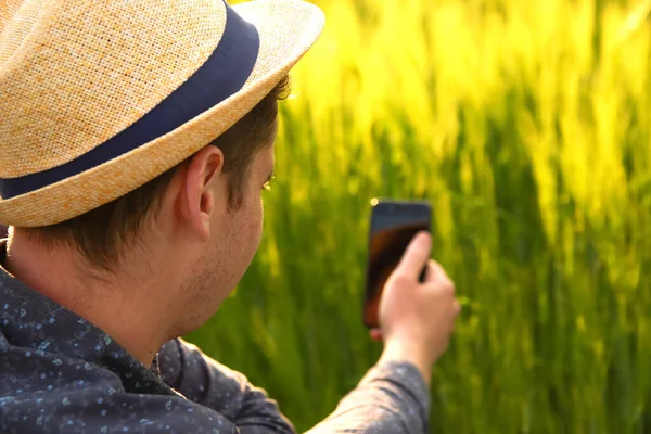 전화를 밭에서 일하는 농부가 스마트폰으로 스프링클러 시스템을 점검하고 조율하고 있습니다 — 스톡 사진