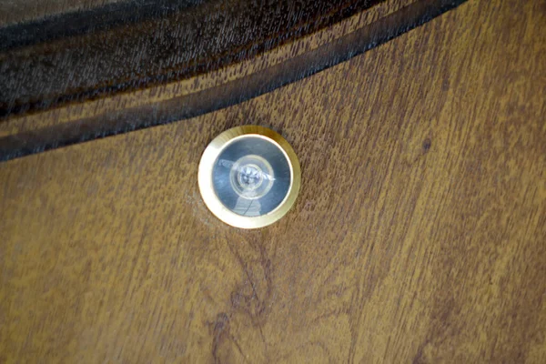 Close up eye hole on wood. close up, door lens peephole on white wooden texture. Door eye, at the door. Out of focus.