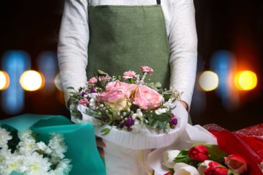 Çiçekçi kadın. Çiçekçiler geceleri güzel buketler yaparlar. Küçük bir iş. Çiçekçide bir kadın çiçekçi. Kadın buketi. Rengarenk çiçeklerden bir buket hazırlıyorum. Odaklanamıyorum.