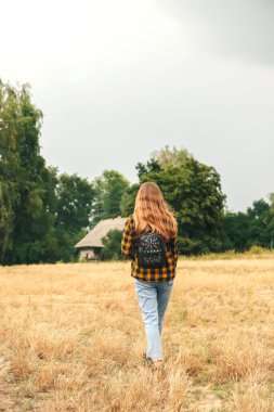 Sırt çantalı kadın. Savana çölünde sırt çantalı hippi kız. Gezgin geçmişi. Turist yaz yaşam tarzı. Sarı kıvırcık saçlı. Ergen tarzı. Yürüyüş. Yürüyen doğa. Dikey.