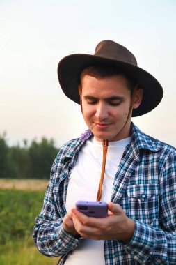 Çiftçi telefonu kullanıyor. Genç bir çiftçi özenle sulama sistemiyle ilgilenir, merkez fıskiyeleri inceler ve ince ayar yapar..