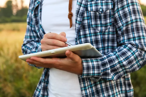 Tarlada çiftçi. Bir çiftçi, tarım görevlerinde yardımcı olmak için kendini adamış bir uygulamayı tablet bilgisayarında kullanır. Ellerini kapat..
