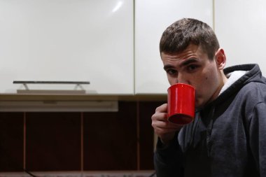 Mutfak arka planında kırmızı bardaktan içen adam. Geleneksel sabah sıcak enerji içeceği. Uzayı kopyala Odaklanamıyorum.