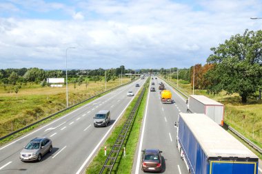 Birden fazla şeritli bir otoyolun hava görüntüsü, trafik akışı ve taşımacılık altyapısı maddeleri ve trafik yönetimi raporları için uygun araç ve kamyonların hareketini gösteriyor.