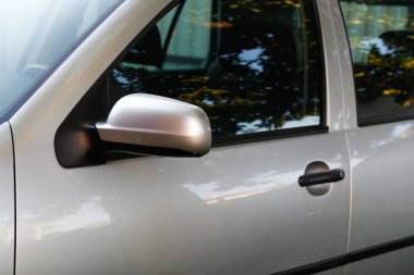 Gri hatchback araba kapısı, ayna ve pencere detayları, otomotiv tasarımı. Gri hatchback araba yakın plan, kapı kolu, yan ayna ve pencere yansıması..