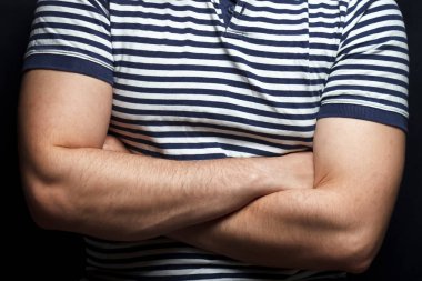 Ellerin iyi tanımlanmış pazıların üzerinde kesişiyor. Erkeğin kaslı kollarına yakın çekim. Güç ve beden eğitimi kavramı. Striptiz tişörtlü kaslı adam..