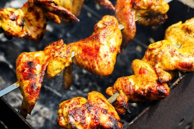 Izgara tavuk kanatları ızgarada cızırdıyor, altın gibi, çıtır çıtır bir dışı ve ızgaradan yükselen dumanı var. Kanatların zengin dokusu ve tadı.