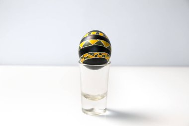 Beyaz zemin üzerine kurulmuş parlak sarı ve siyah bir Paskalya yumurtası cesur ve modern bir kontrast oluşturuyor. Asgari Paskalya.