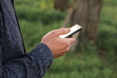 Dışarıda cep telefonu kullanan bir adam. Yeşil arkaplan, model ekran, 10G teknoloji konsepti, Çin 'de modern dijital yaşam tarzı.