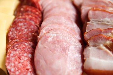 Bir panoda sosis ve dilimlenmiş jambon setinin üst görüntüsü kahvaltı konsepti için mükemmel. Lezzetli bir çeşit dilimlenmiş sosis ve jambon..