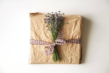Doğal bir kurdeleyle bağlanmış çiçek desenli güzel bir çevre dostu hediye kutusu. Kutu taze lavanta ile süslenmiş, sürdürülebilir ve doğadan esinlenilmiş bir tema sergiliyor..