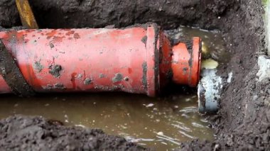 Patlayan Kanalizasyon Borusu. Su ve atık fışkırıyor. Şehir Altyapı Sorunu. Bulanık su, görünür atık ve karmaşık kablolar, kritik kentsel altyapı sorununu gösteriyor.
