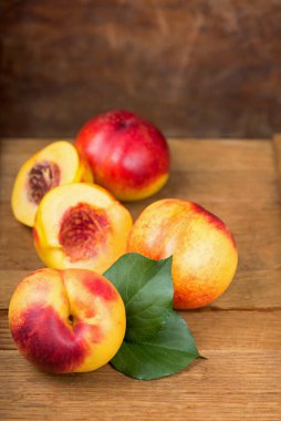 fresh nectarines with leaves on wooden background